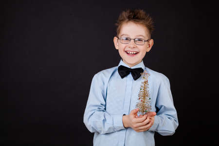 Little boy with Christmas tree over the blackの写真素材