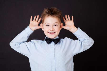 Little boy with funny face on black backgroundの写真素材