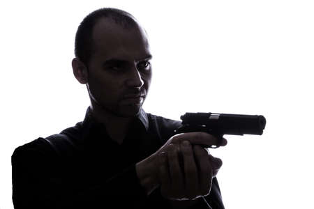 One caucasian  man holding gun portrait silhouette in studio isolated white backgroundの写真素材