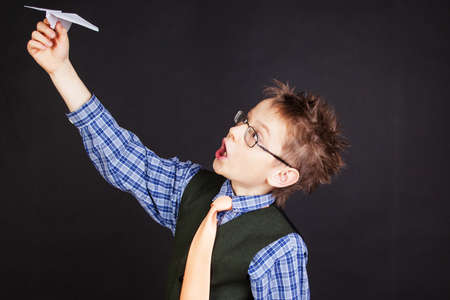 Cute boy with paper plane against the black