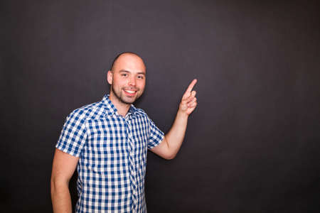 Young happy man pointing  his finger to the copy spaceの写真素材