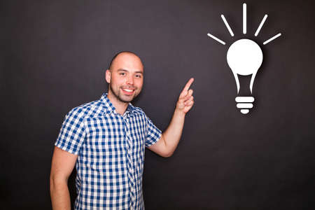 Young happy man pointing  his finger to the bulbの写真素材