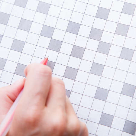 Close up view of a blank crossword puzzle grid with black and white squares and a pencilの写真素材