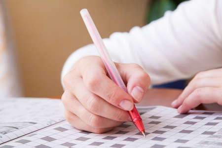Close up view of a blank crossword puzzle grid with black and white squares and a pencilの写真素材