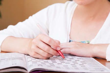 Young  beautiful woman doing crosswords in roomの写真素材