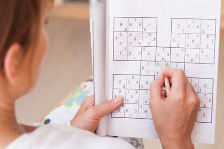 Young  beautiful woman doing crosswords in roomの写真素材