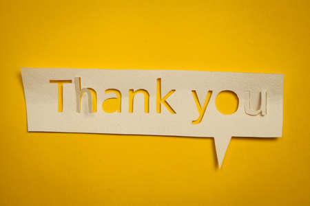 Speech bubble Thank you cut out from paper against yellow backdropの写真素材