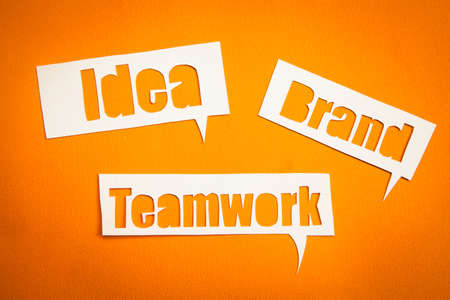 The words idea, teamwork and brand in speech bubbles against orange backgroundの写真素材