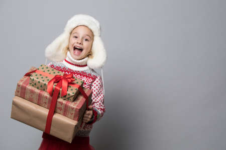 Smiling funny child in fluffy hat holding Christmas gift in hand.の写真素材