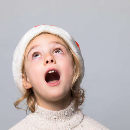 Shocked and surprised kid with red Christmas hat.