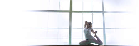 Yoga woman posing in front of the windowの写真素材