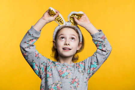 Cute little girl with bunny ears and basket full of Easter eggs