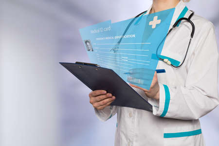 Doctor examines patient electronic card on the blurred medical backgroundの写真素材