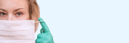 Closeup of the woman in rubber gloves putting on protective mask.の写真素材