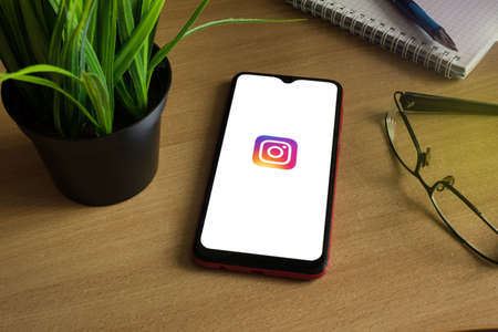 Minsk 12.05.2020. Smartphone on a wooden table with image of Instagram.のeditorial素材