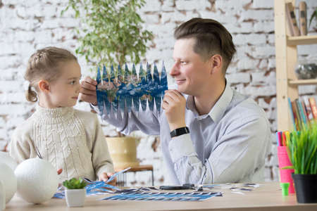 Dad and daughter create a model of planet Earth.の写真素材