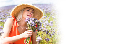 Photo of beautiful happy woman in stylish dress smiling on blue fieldの写真素材