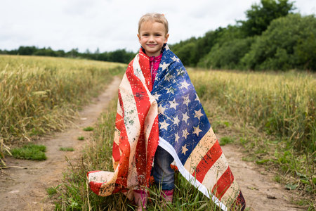 Little girl with american flag on the fieldの写真素材