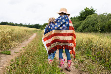 Little girl with american flag on the fieldの写真素材