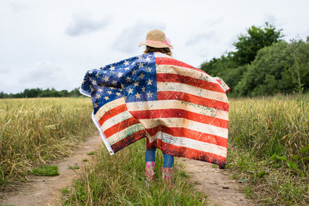 Little girl with american flag on the fieldの写真素材