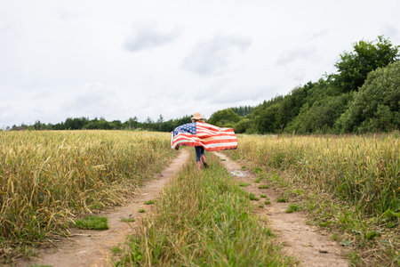 Little girl with american flag on the fieldの写真素材