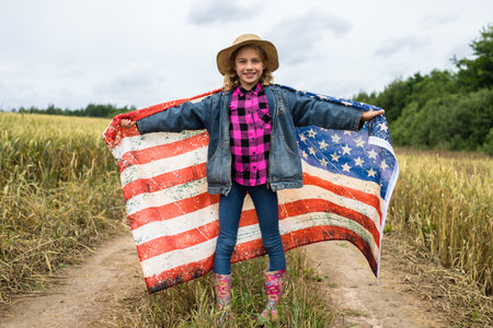 Little girl with american flag on the fieldの写真素材
