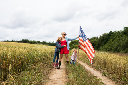 Girl with children on the field stands with a USA flagの写真素材