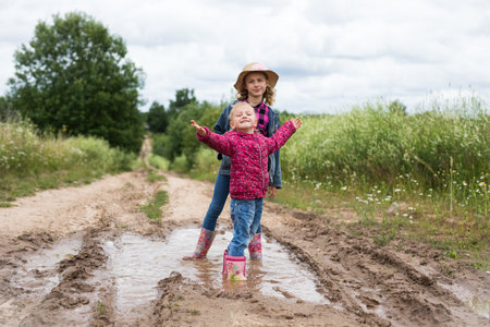 Two girls run through the puddles and play.の写真素材