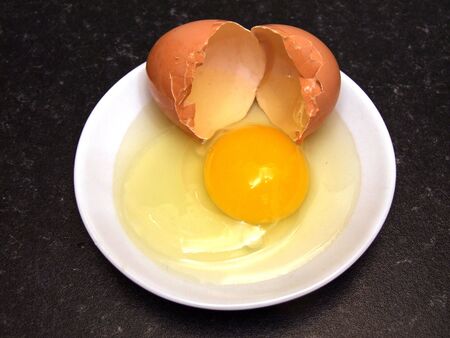 Egg shell, yolk and white for healthy cooking on a small plate