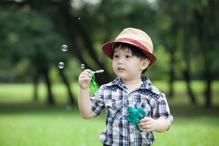 Little asian boy playing and blowing bubble in the gardenの写真素材