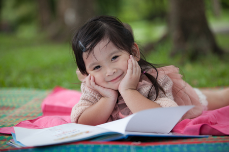 Little girl reading book in the gardenの写真素材