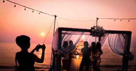 Silhouette of woman taking photo of wedding arch on the beachの写真素材