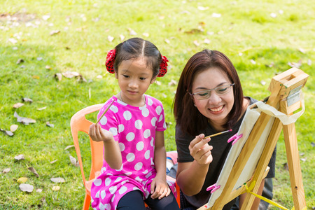 Littel asian girl painting with easel in gardenの写真素材