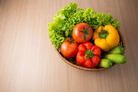 Fresh vegetable prepared in bowl on wooden table, Lettuce cucumber bell pepper tomato in bowl on wooden table preparing for making salad.の写真素材