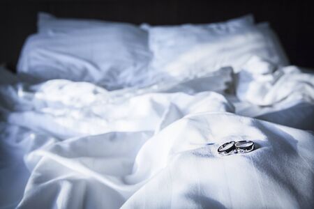 Couple wedding ring on on wrinkly blanket on bed in Valentine day in morning time . Toned color photoの写真素材