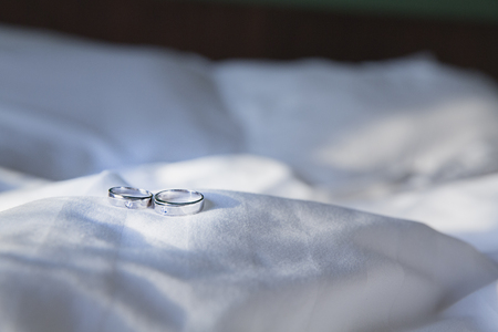 Couple wedding ring on on wrinkly blanket on bed in Valentine day in morning time . Toned color photoの写真素材