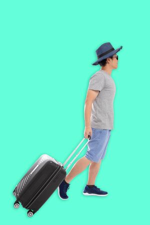 Tourist backpack man in casual wear walking with luggage isolated on green backgroundの写真素材