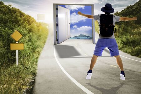 Tourist jumping on road with opened door to the sea paradise, Unusual travel vacation beach conceptの写真素材