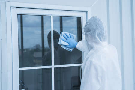 Man in virus protective suite and mask spraying alcohol cleaning covid19 infected area, Virus...