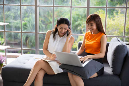 Two Asian woman colleaque with computer latop working from home, New normal working  lifestyle conceptのeditorial素材