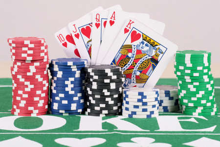 Poker Chips With Cards - Poker chips in five different colors on a table with cards.