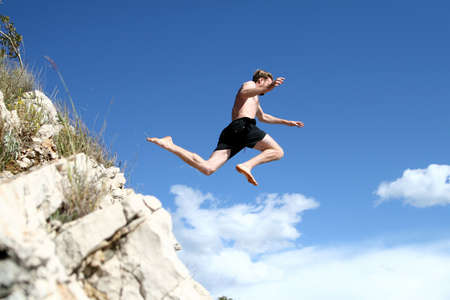 Taking Off A young man jumps from a cliff into the sea!の写真素材
