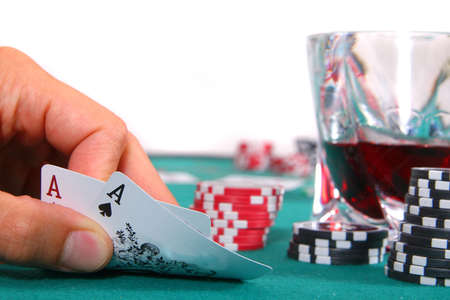 Pocket Rockets - A hand is showing two aces on a poker table with a glass of red liquor. Isolated over white.のeditorial素材