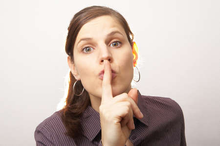 Young woman with her finger over her mouth.