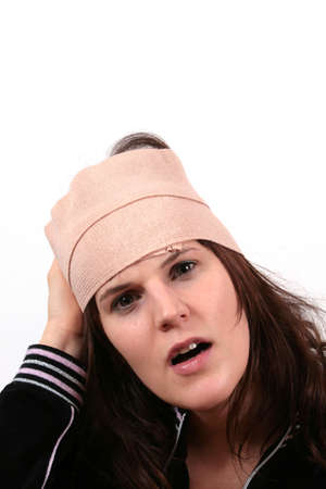 Head Hurts - A young woman holds her head with bandage in pain.の写真素材