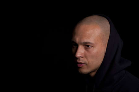 Stylish young man with hoddie over a black background.の写真素材