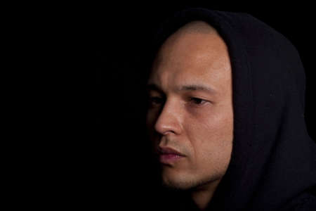 Stylish young man with hoddie over a black background.の写真素材