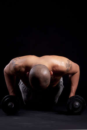 Young bald strong man is working out over black background.の写真素材