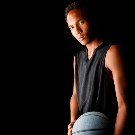 Young black basketball player over black background. Young, fresh and stylishの写真素材