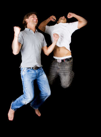 Two young successfull jumping in joy! Two handsome multiracial models.の写真素材